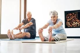Older couple stretching together on mats at home