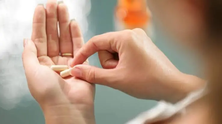 Person taking a daily supplement capsule